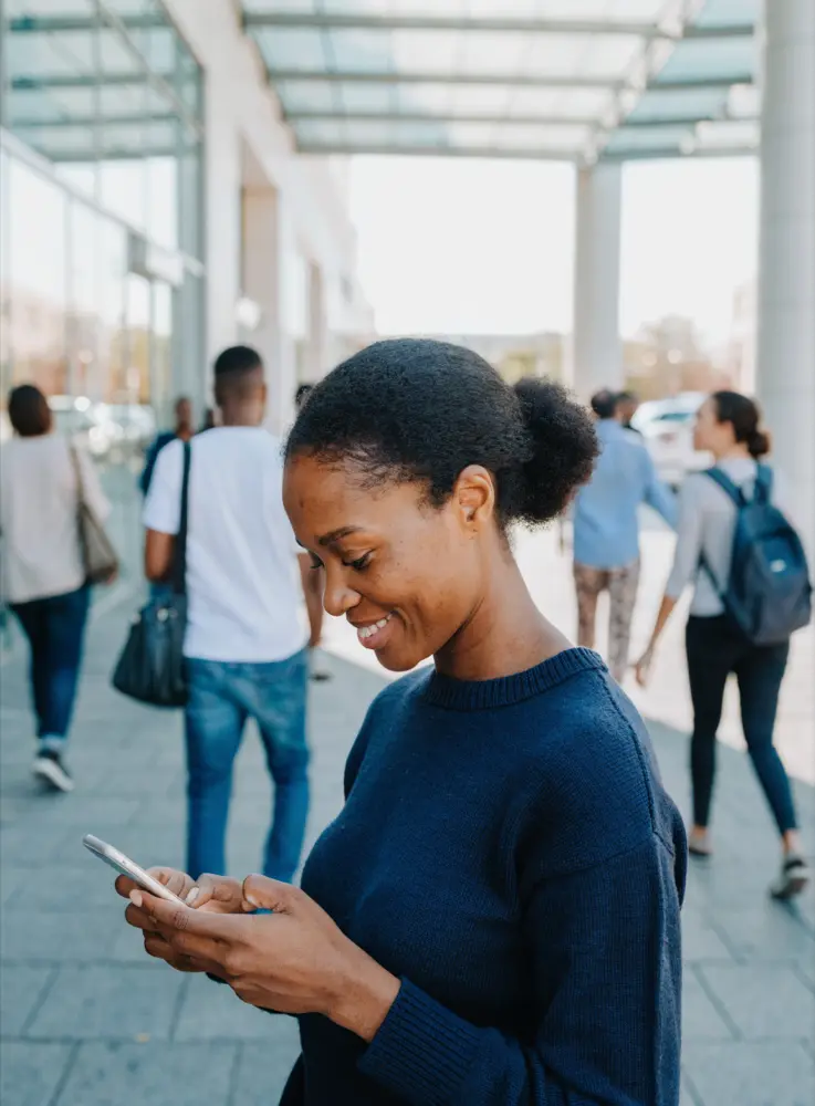A woman checking her phone outside a busy shopping centre